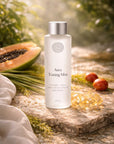 Aura Toning Mist bottle on a natural stone surface with a papaya and leaves in the background