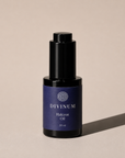 A 30 ml bottle of Divinum Halcyon Oil, featuring a dark purple label and a black dropper cap, set against a warm beige background with a soft shadow.