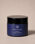 A 50g jar of Divinum Solstice Crème Exfoliant, featuring a deep purple label and a black lid, set against a solid beige background.