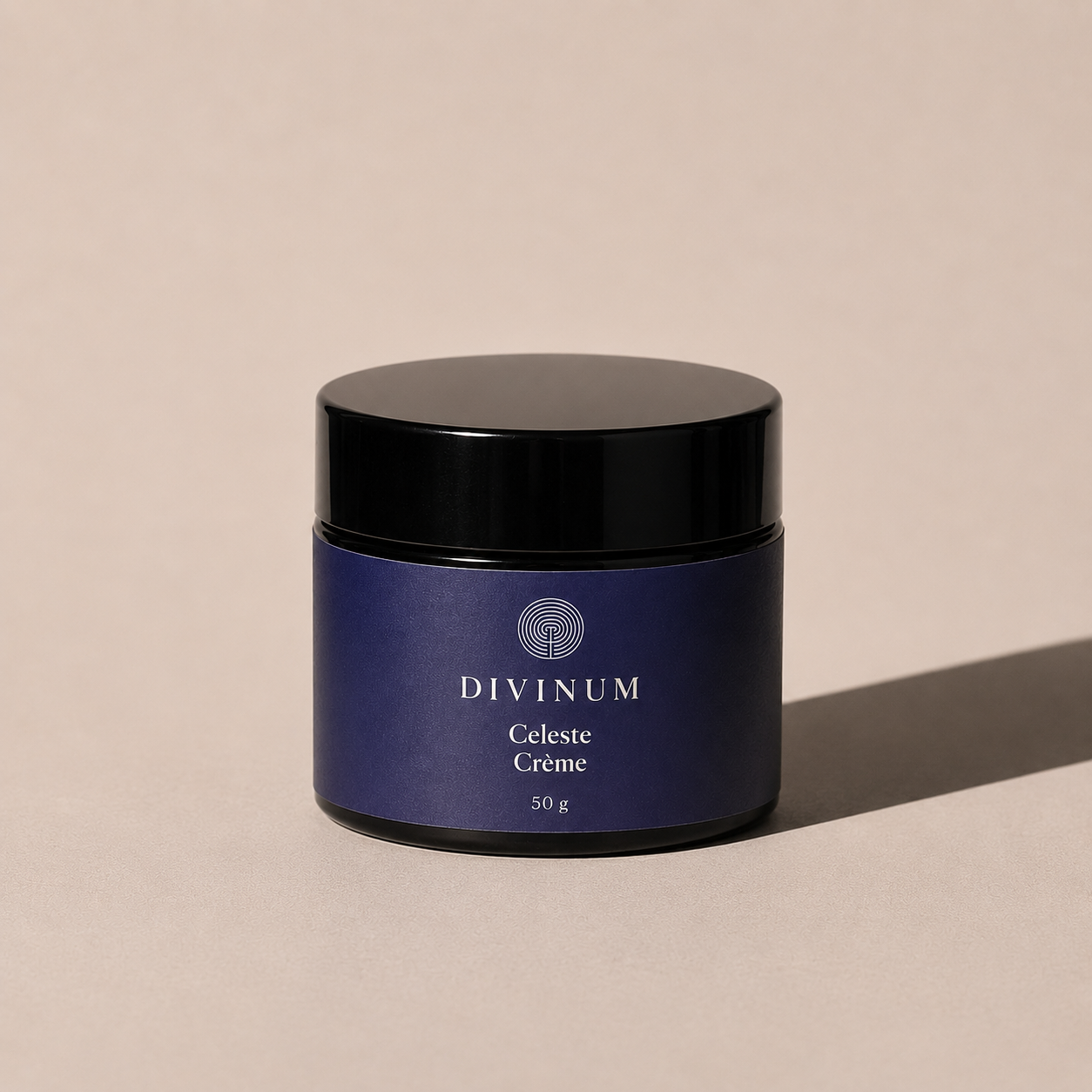 A 50g jar of Divinum Celeste Crème cosmetic cream, featuring a deep purple label and a black lid, set against a warm beige background with a soft shadow.