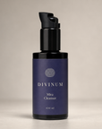 A 100 ml bottle of Divinum Mira Cleanser with a dark purple label and a violet pump dispenser, set against a neutral beige background.