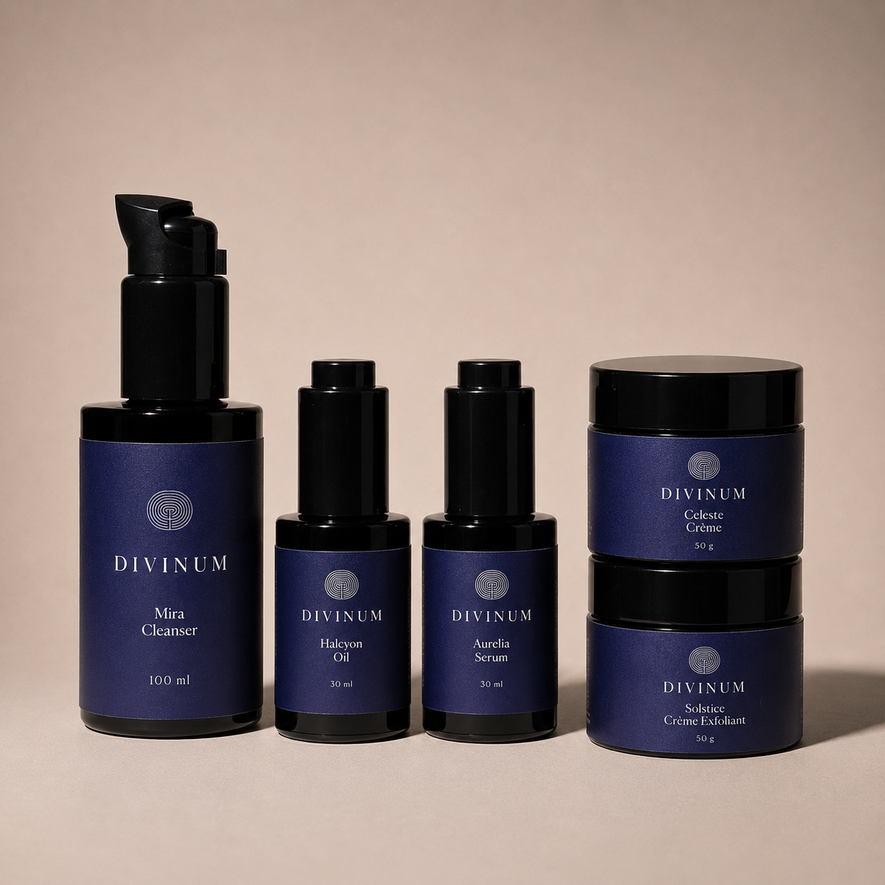 A set of five Divinum skincare products in dark violet and black packaging, arranged neatly on a warm beige background. The set includes a Mira Cleanser pump bottle, a Halcyon Oil dropper bottle, an Aurelia Serum dropper bottle, and two Creme jars stacked vertically.