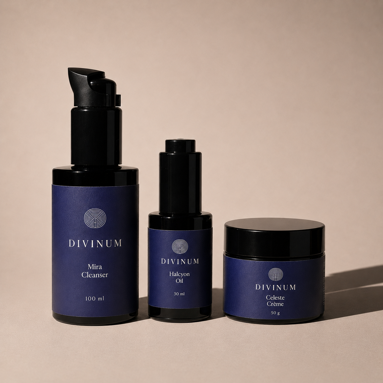 Three Divinum skincare products in dark violet and black packaging, including a pump bottle of Mira Cleanser, a dropper bottle of Halcyon Oil, and a jar of Celeste Creme, arranged on a warm beige background.